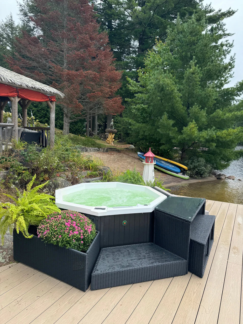 Muskoka 14-Jet 4-Person Spa Canadian Spa Company hot tub showing green LED lighting in garden setting next to lake.
