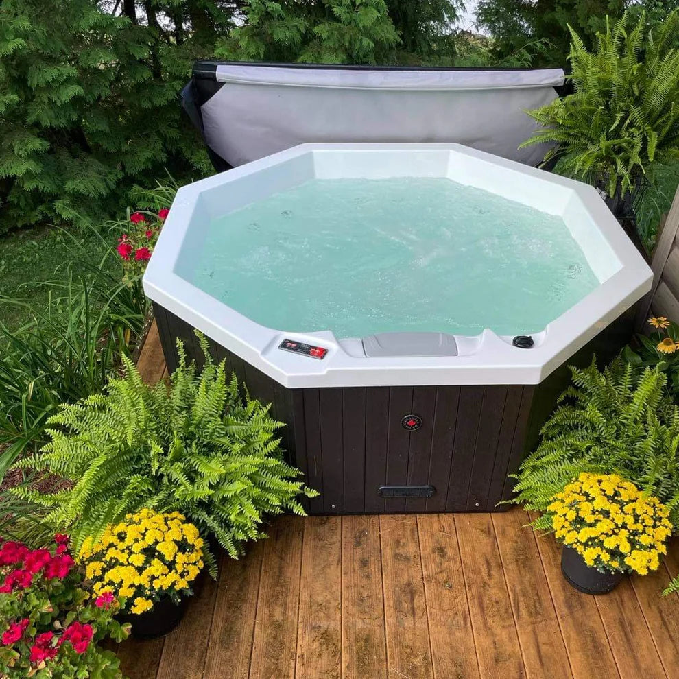 Muskoka 14-Jet 4-Person Spa filled with jet bubble system on, surrounded by decking and garden plants.