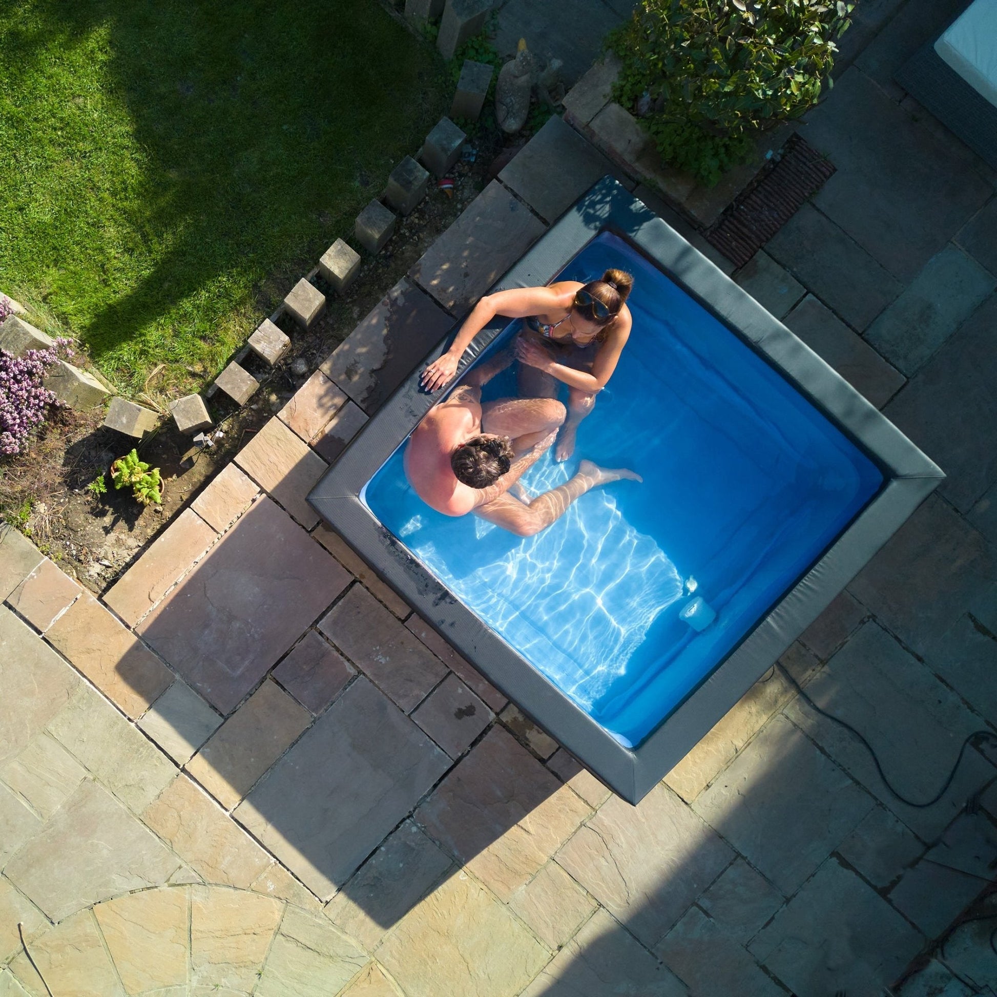 Garda 4 Person Eco Foam Hot Tub by Wave Spas lifestyle image showing couple enjoying in their back garden on birds eye view. 