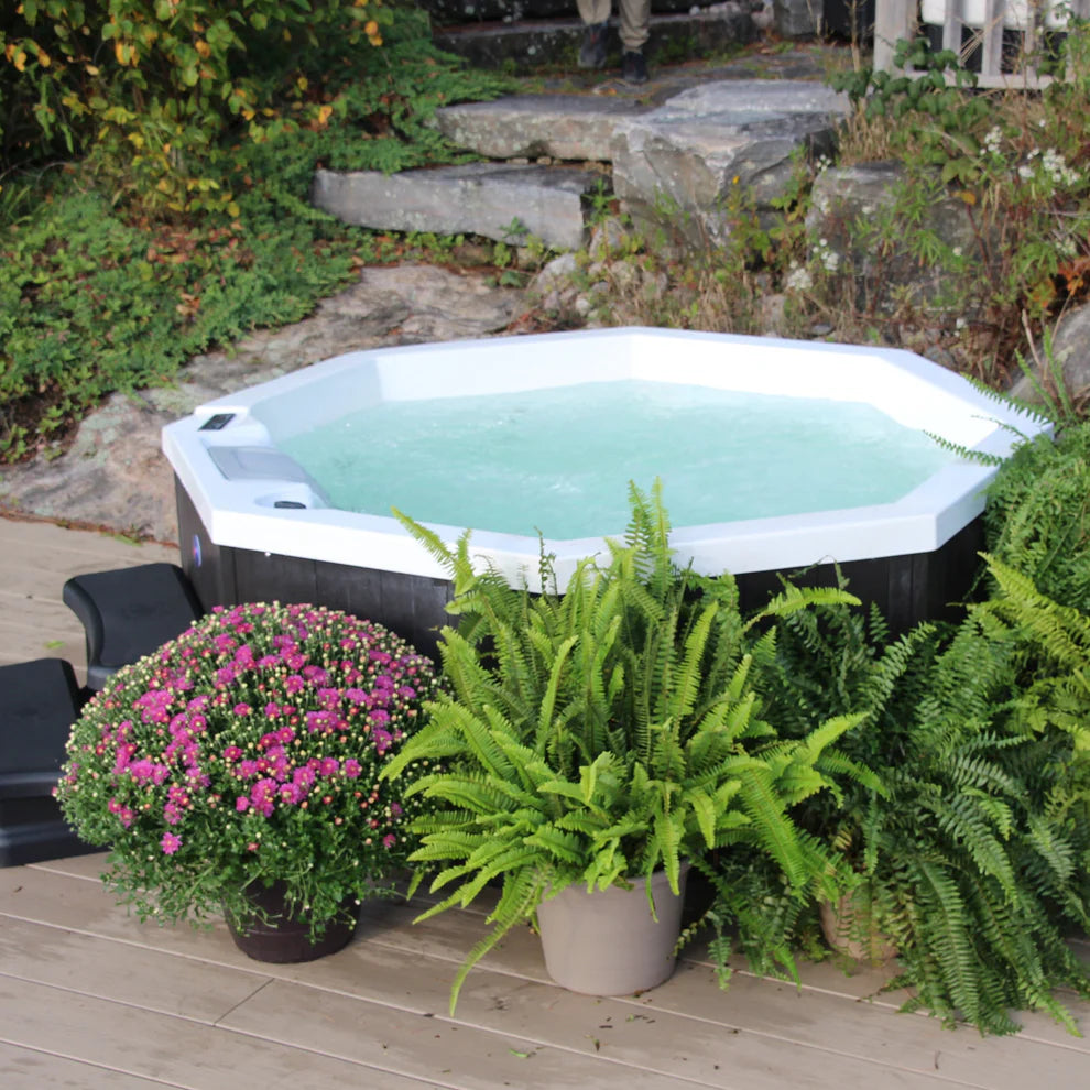 Muskoka 14-Jet 4-Person Spa by Canadian Spa Company and Nordic Harmony filled with water and surrounded by garden landscaping. 