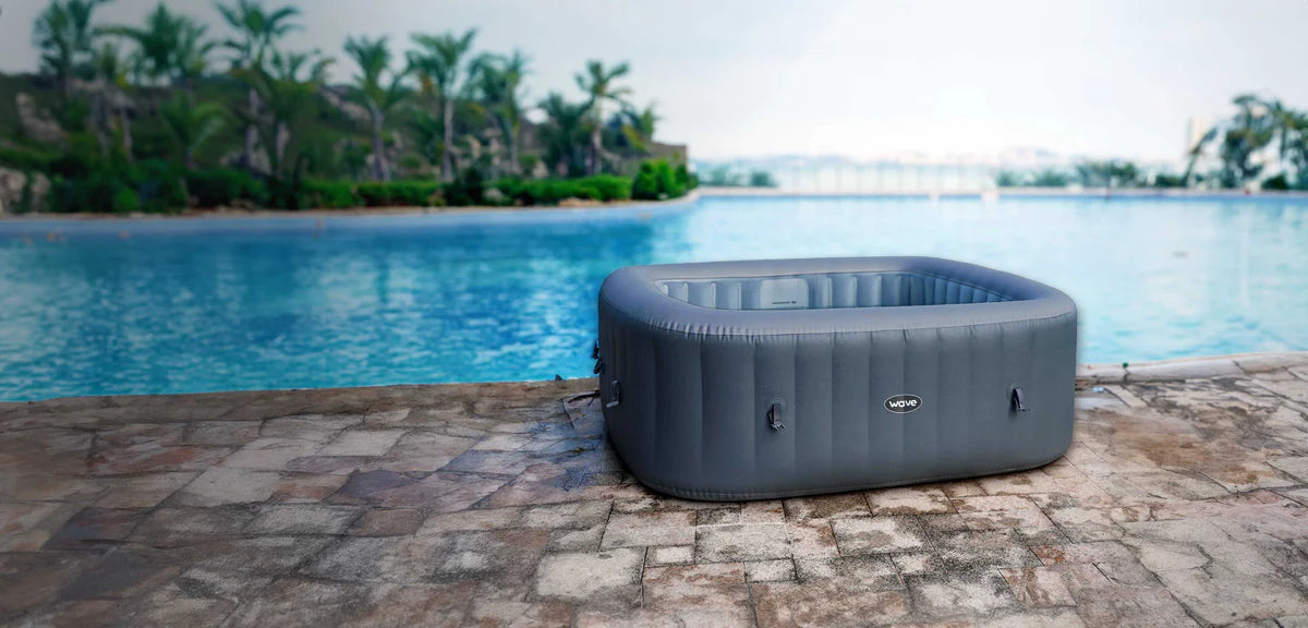 Wave Spas Pacific Inflatable Hot Tub in grey, inflated and empty and situated next to swimming pool. 