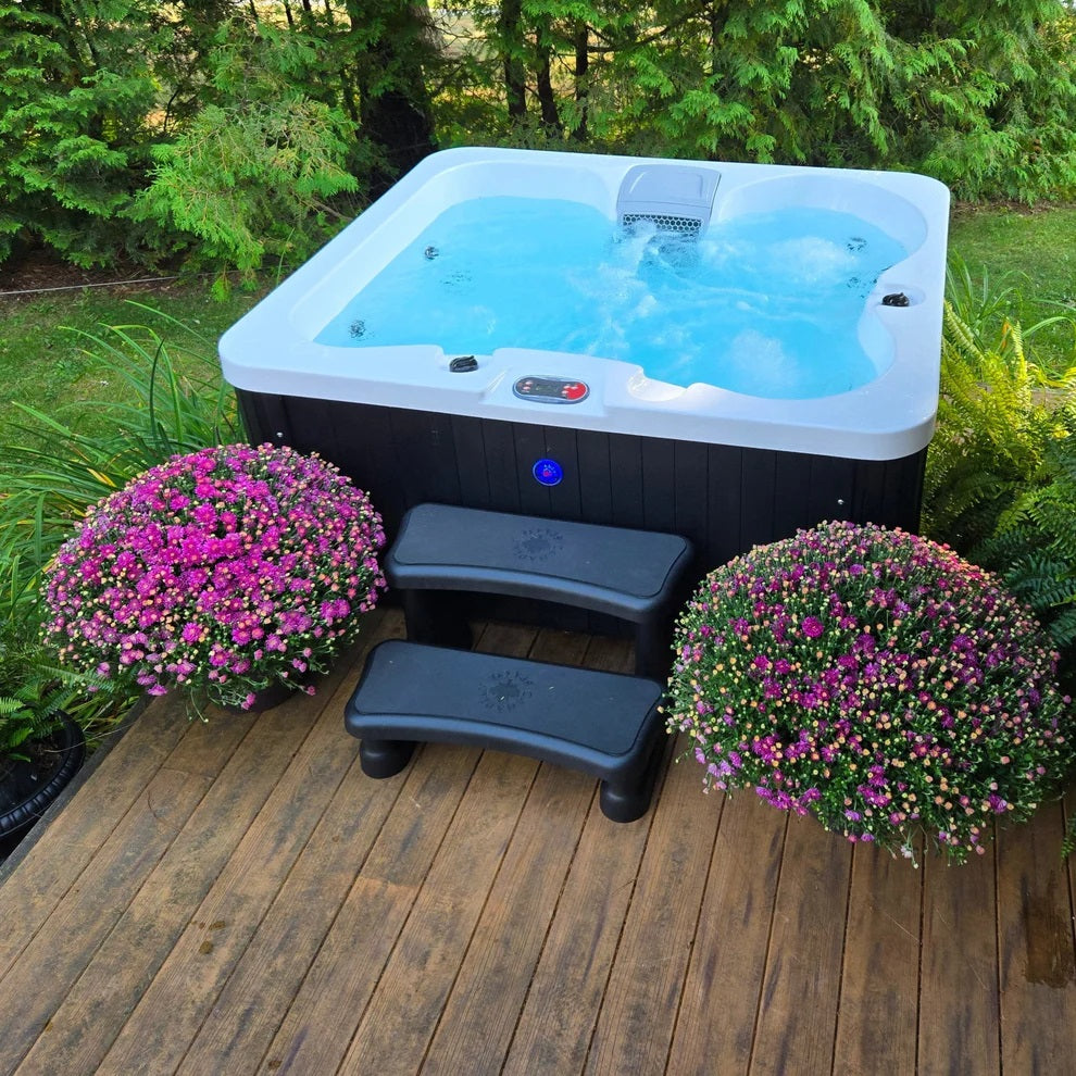 Manitoba jet spa by Canadian Spa Company showing water jets working, with steps leading up to the spa on garden decking area. 