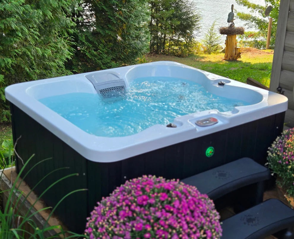 Manitoba jet spa filled with clear blue water with jets operational, set in green garden setting. 